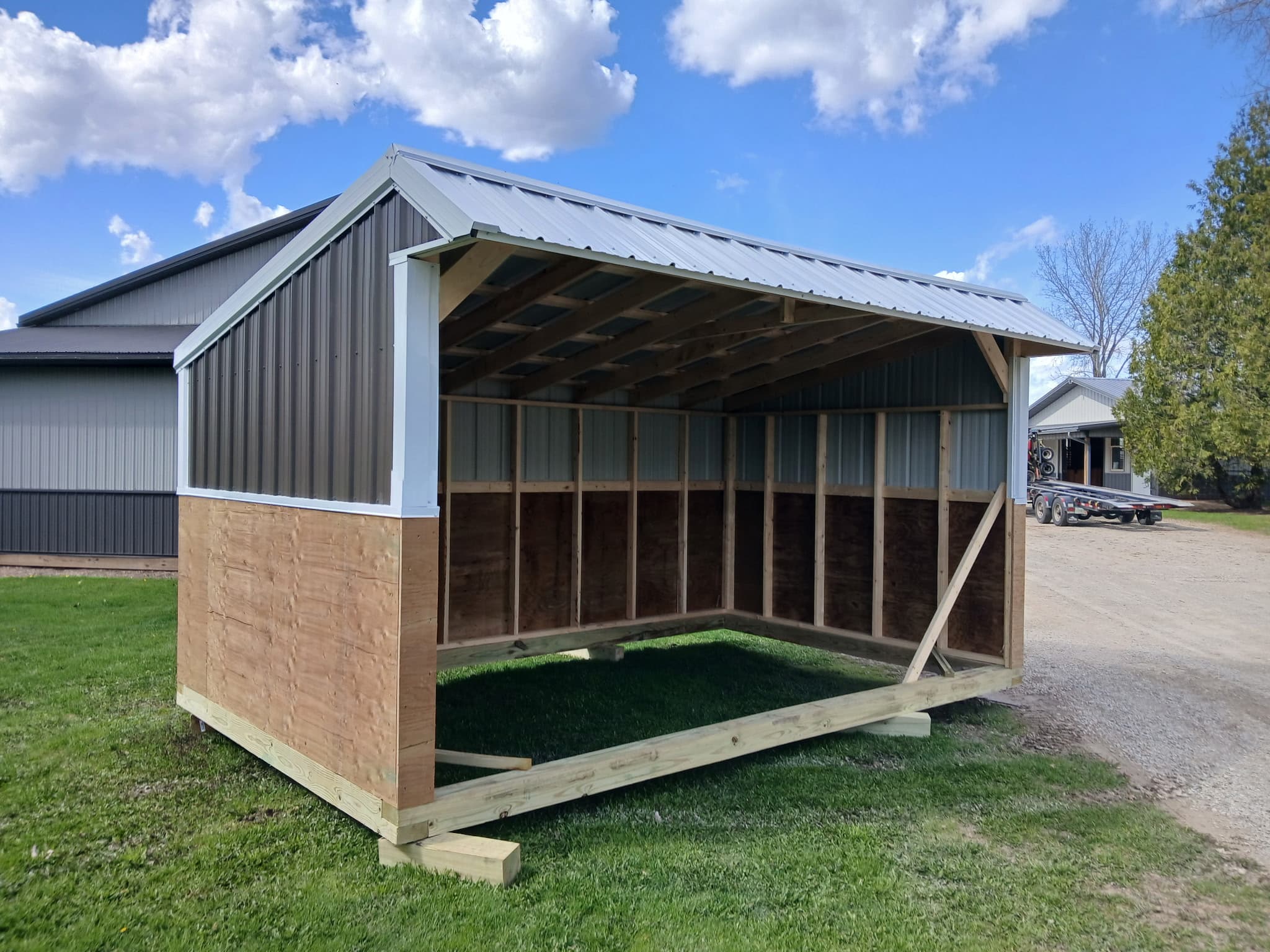 Charcoal horse shelter with white trim, an open front and wood framing.